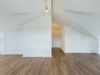 Stilvolle Dachgeschosswohnung mit flexibler Raumaufteilung und Balkon - Wohnbereich mit Blick in den Flur